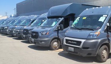 A row of commercial fleet vans and trucks lined up at the shop