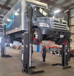Amazon box truck raised on heavy-duty lifts inside the shop